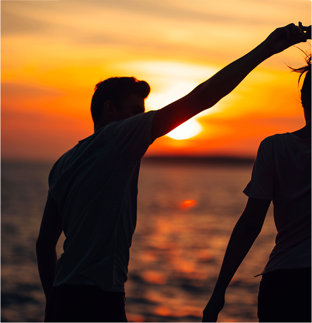 Two people playing on the beach at summer sunset
